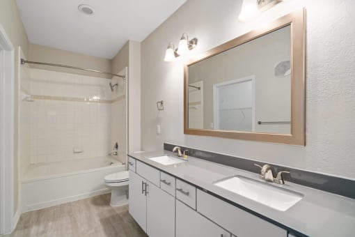 a bathroom with a white tub and a white toilet next to a white sink with a mirror