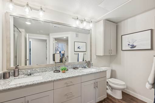 A bathroom with a large mirror, a toilet, and a sink.