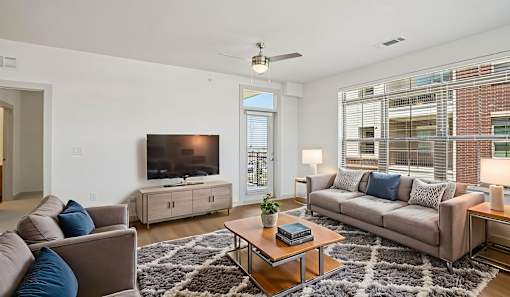 A living room with a grey couch, a wooden coffee table, and a flat screen TV.