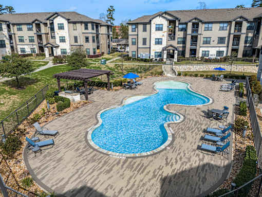 A large swimming pool with a wooden deck and lounge chairs.