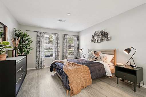 A bedroom with a bed, nightstand, and a plant.