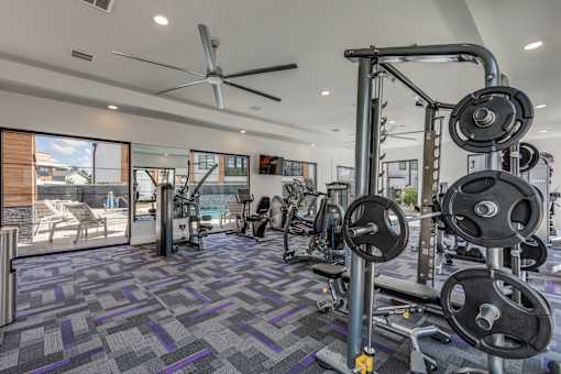 a gym with weights and cardio equipment in a home with a pool