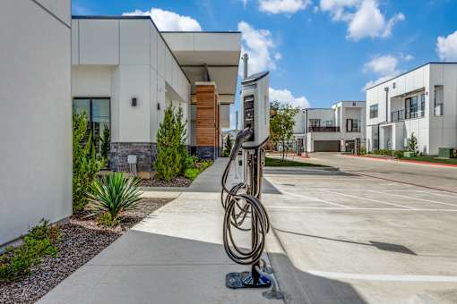 A sculpture of a large metal ring is in the foreground of a modern building parking lot.