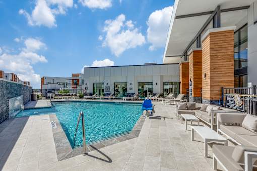 A man in a blue shirt is sitting by a pool.