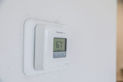 a white thermostat with a digital clock on it