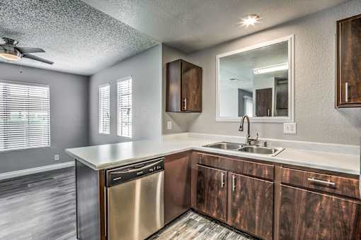 A modern kitchen with a stainless steel dishwasher and wooden cabinets.