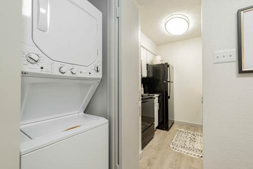 A white dishwasher is next to a black refrigerator in a small kitchen.