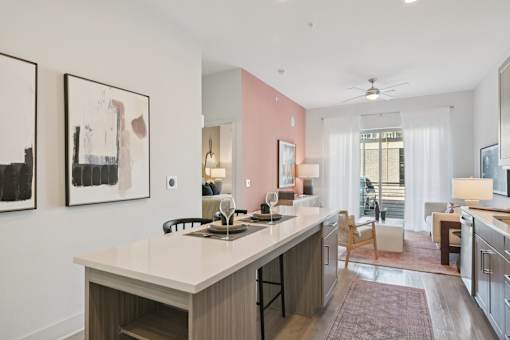 A kitchen with a white countertop and a pink wall.