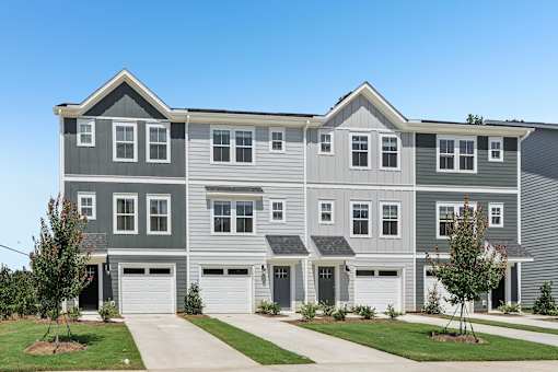 A grey and white townhouse with a garage door.