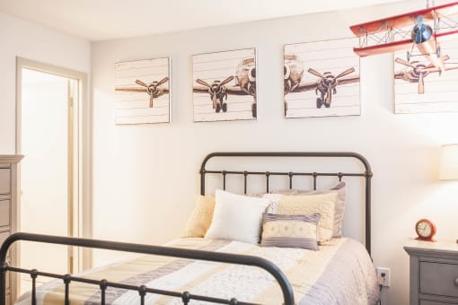 a bedroom with a bed and pictures of planes on the wall