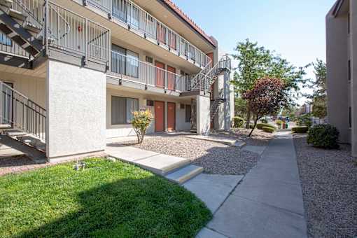 an exterior view of an apartment building with a sidewalk and grass