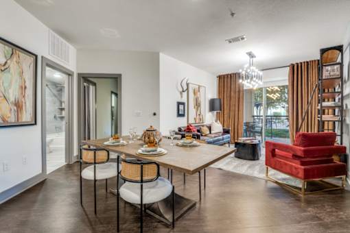 A dining room with a table set for two and a red chair.