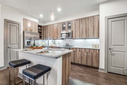 A kitchen with a marble countertop and bar stools.
