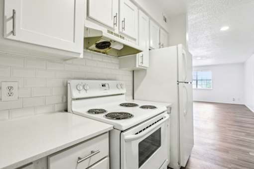 A white kitchen with a stove and refrigerator.
