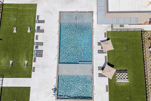 A large rectangular pool with a blue tiled edge and a person sitting on the edge.
