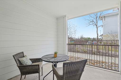 A balcony with a table and two chairs.
