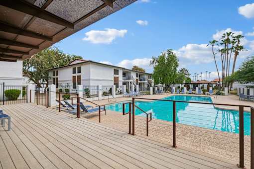 A wooden deck with a pool and a building in the background.