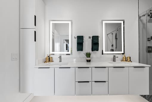 A white bathroom with two sinks and two mirrors.