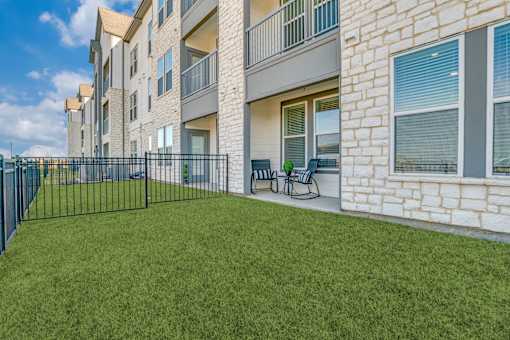 A grassy area in front of a building with a black fence.