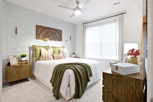 A bedroom with a bed, a ceiling fan, and a wooden dresser.