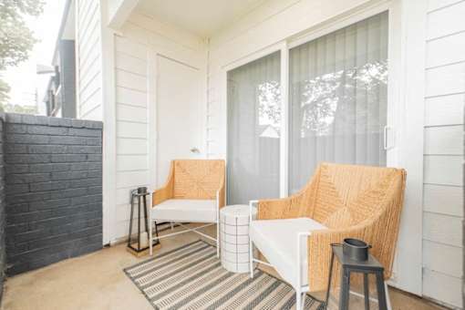 A white chair with a tan cushion is on a porch.
