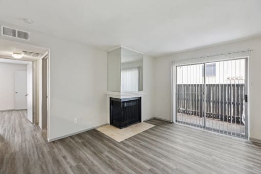 an empty living room with a fireplace and a door to a balcony