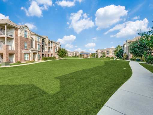 A sunny day at a residential area with apartment buildings and a well-maintained lawn.