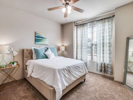 A bedroom with a large bed and a ceiling fan.