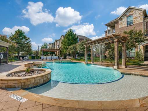A large outdoor swimming pool surrounded by a stone border.