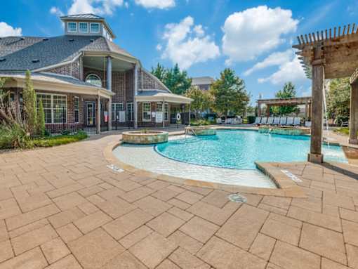 A large outdoor swimming pool area with a building in the background.