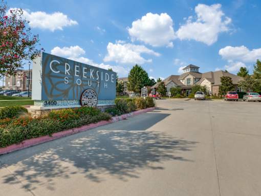 A sign for Creekside South with a tree in front of it.