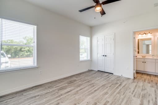 an empty living room with a ceiling fan and a window