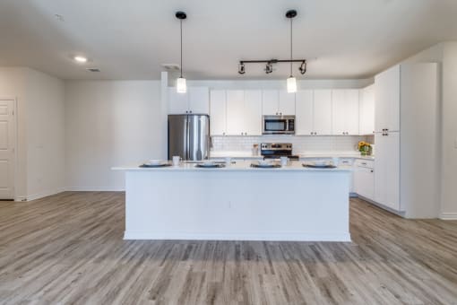 an open kitchen and living room with white cabinets and a large island