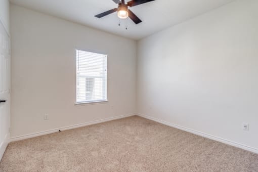 an empty room with a ceiling fan and a window