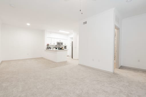 an empty living room and kitchen with white walls and flooring