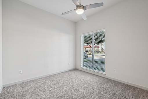 A room with a ceiling fan and carpeted floor.