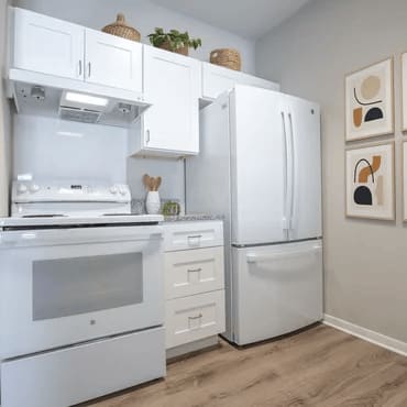 A white kitchen with a refrigerator, oven, and cabinets.