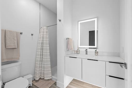A white bathroom with a towel hanging on the wall.