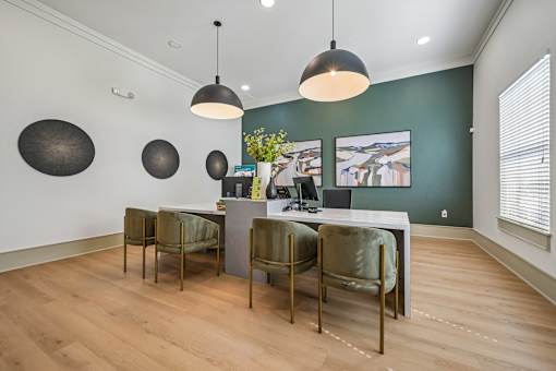 A room with a desk and chairs and a painting on the wall.