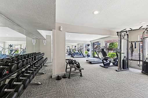 A gym with a variety of equipment including treadmills, weights, and exercise machines.
