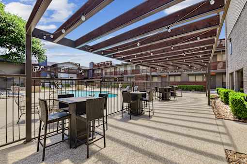 A patio with a table and chairs under a wooden pergola.