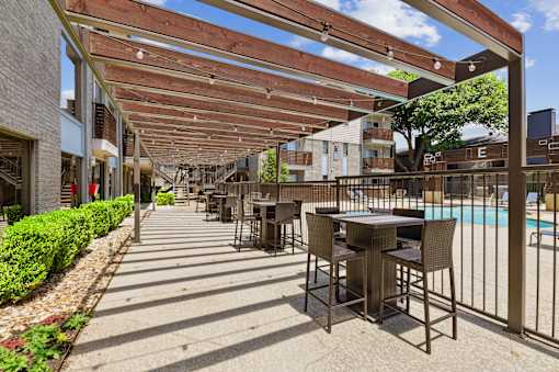A patio with a table and chairs is covered by a wooden roof.