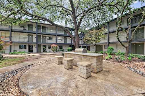 A courtyard with a brick structure in the middle and apartment buildings in the background.