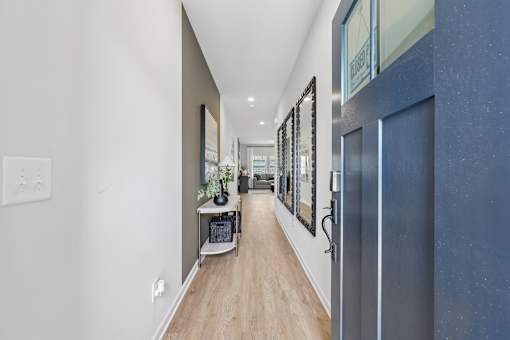 A long hallway with a blue door and pictures on the wall.