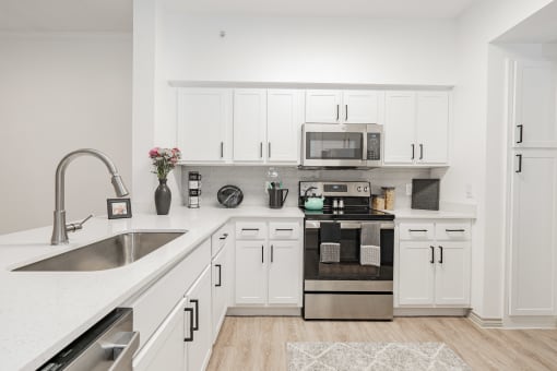 a spacious kitchen with white cabinets and stainless steel appliances