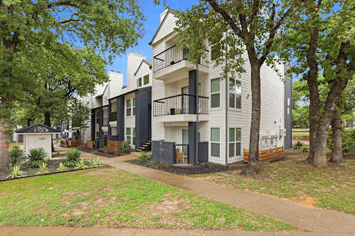 A row of modern townhouses with balconies and trees in the front yard.