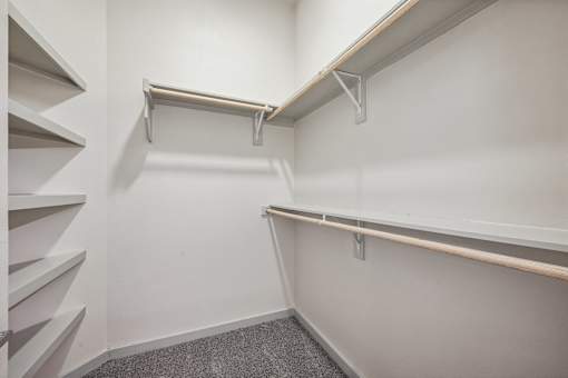 A white wall with a metal rail and a grey carpet.