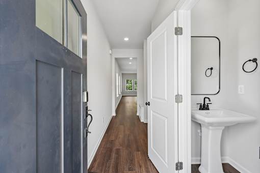 A long hallway with a sink and mirror at the end.