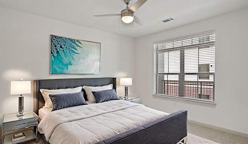 A bedroom with a large bed and a ceiling fan.