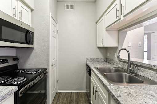 A kitchen with a stove, microwave, and sink.